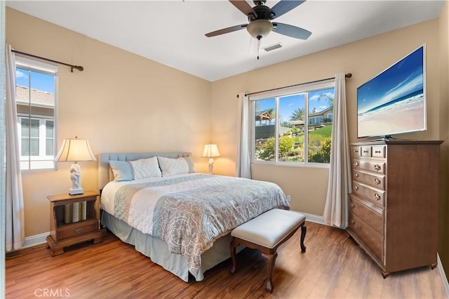 bedroom featuring baseboards, ceiling fan, visible vents, and light wood finished floors