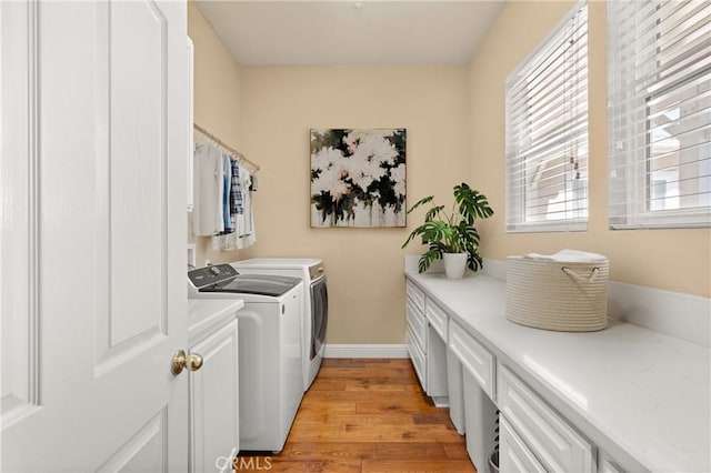 laundry room with baseboards, cabinet space, washer and clothes dryer, and light wood finished floors