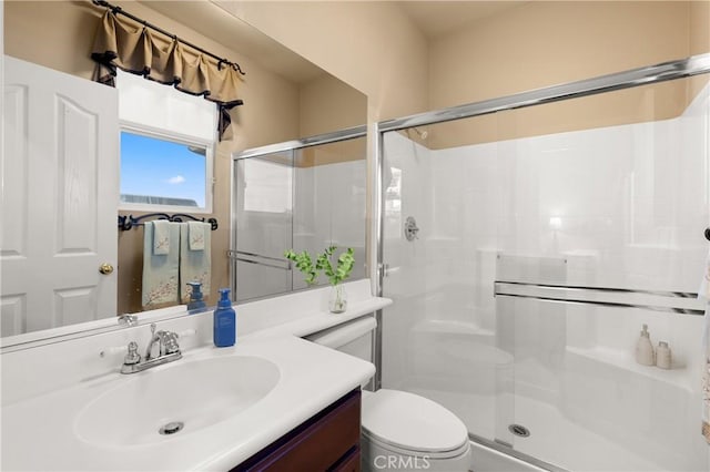 bathroom featuring toilet, a shower stall, and vanity