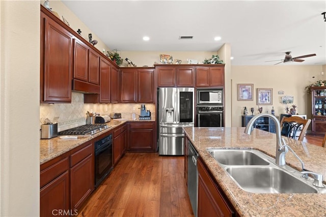 kitchen featuring stainless steel appliances, visible vents, decorative backsplash, a sink, and wood finished floors