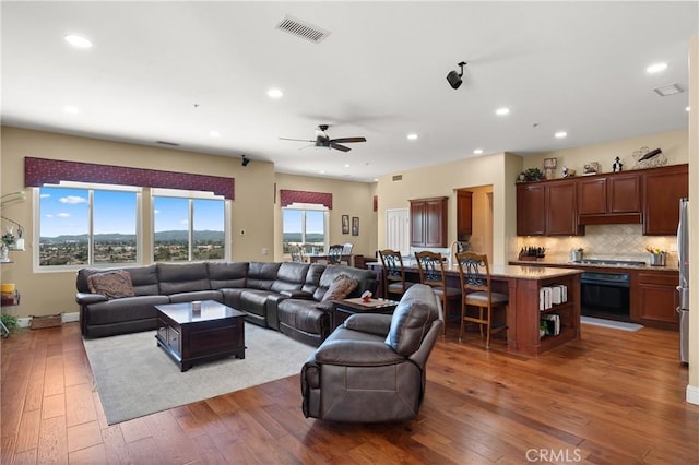 living area with wood-type flooring, visible vents, a ceiling fan, and recessed lighting