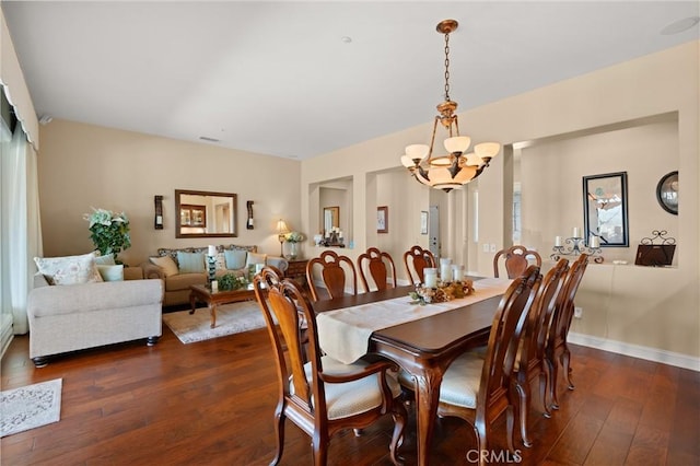 dining space featuring dark wood-type flooring, a chandelier, visible vents, and baseboards