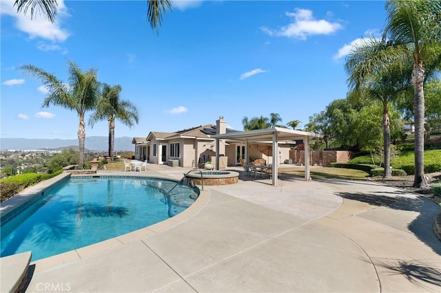 view of swimming pool featuring a pool with connected hot tub, a patio area, and fence