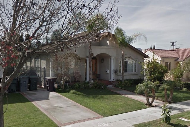 mediterranean / spanish house featuring a front lawn and stucco siding