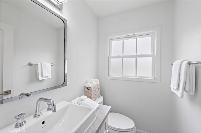 bathroom with toilet, vanity, and baseboards