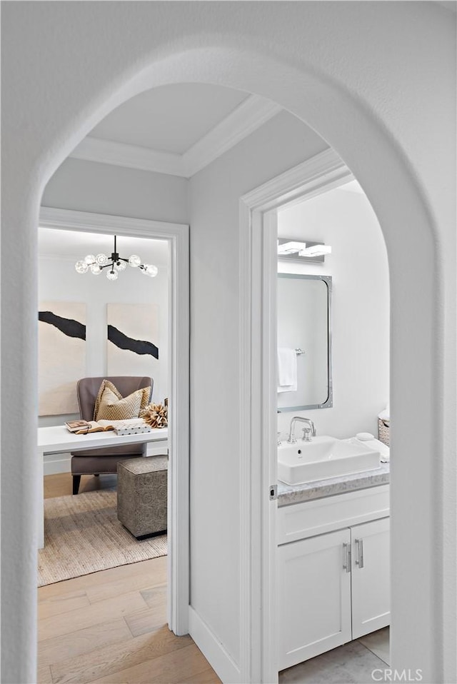 bathroom featuring a chandelier, crown molding, wood finished floors, and vanity