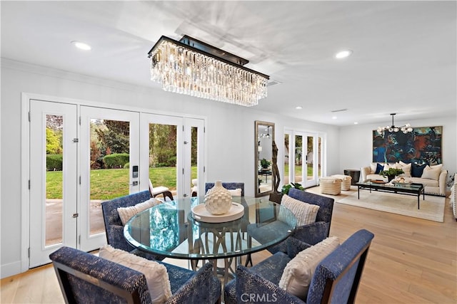 dining area featuring light wood-type flooring, french doors, a notable chandelier, and recessed lighting