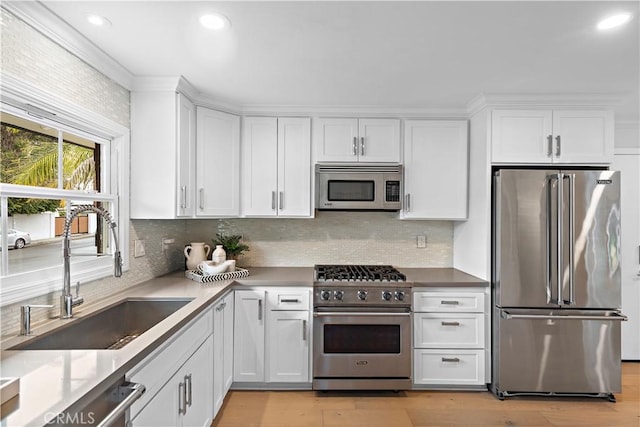 kitchen featuring tasteful backsplash, white cabinetry, a sink, and high end appliances
