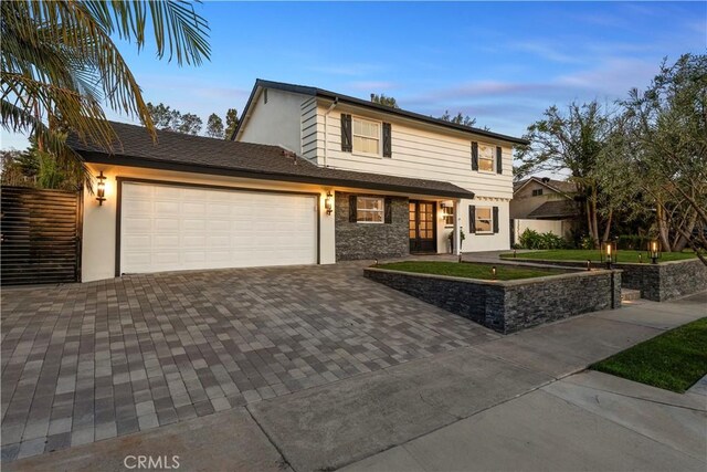 traditional-style home featuring fence, stucco siding, decorative driveway, and a garage