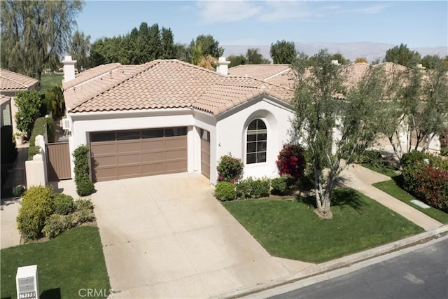 mediterranean / spanish home featuring a tile roof, stucco siding, an attached garage, driveway, and a front lawn