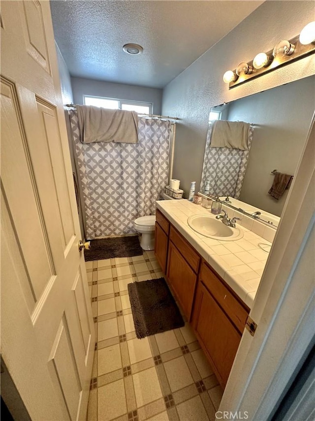 bathroom with a textured ceiling, toilet, tile patterned floors, vanity, and a shower with curtain