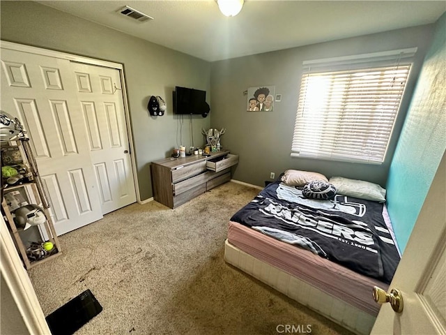 carpeted bedroom with a closet, visible vents, and baseboards