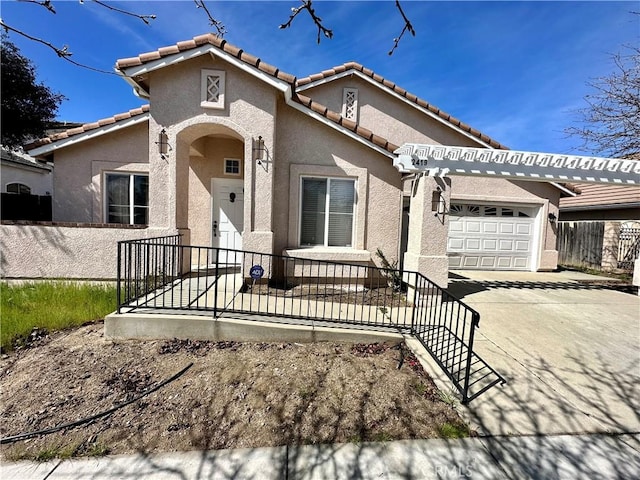 mediterranean / spanish-style home featuring a tile roof, stucco siding, an attached garage, and concrete driveway