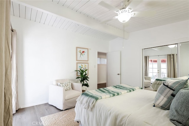 bedroom featuring baseboards, beamed ceiling, french doors, wood finished floors, and a closet