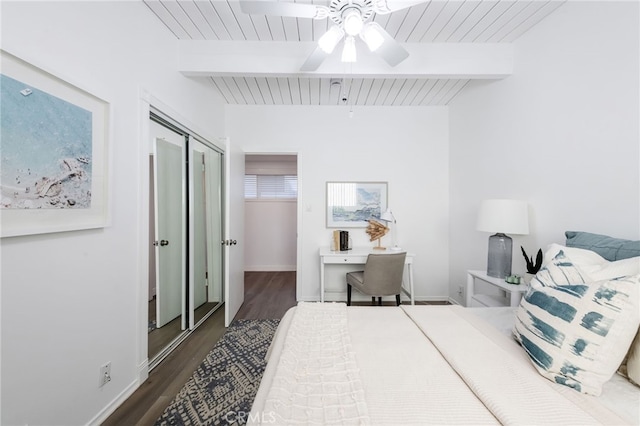 bedroom with beamed ceiling, ceiling fan, dark wood-type flooring, and baseboards