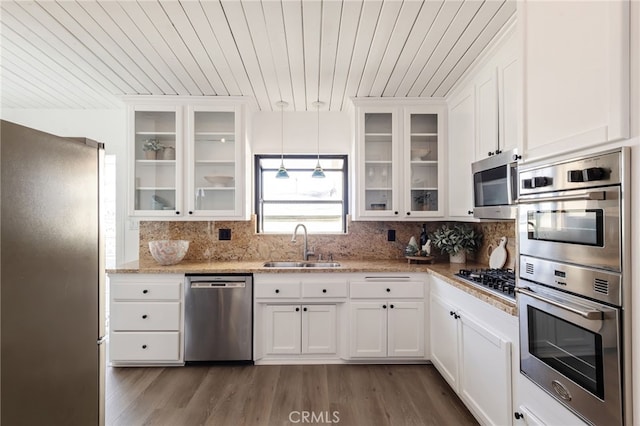 kitchen with a sink, backsplash, stainless steel appliances, white cabinets, and dark wood-style flooring