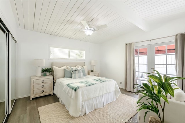 bedroom with multiple windows, french doors, lofted ceiling with beams, and wood finished floors