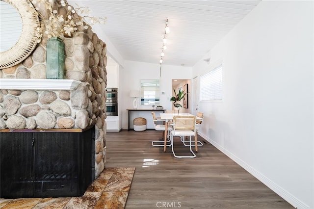 dining space with vaulted ceiling, track lighting, baseboards, and wood finished floors