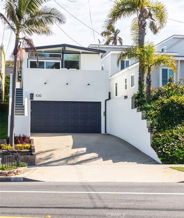 view of front of home featuring stucco siding, a garage, concrete driveway, and stairs