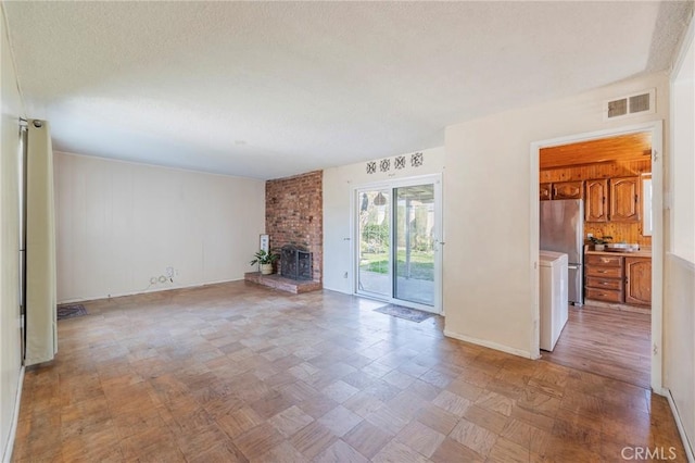 unfurnished living room featuring a textured ceiling, a fireplace, and visible vents