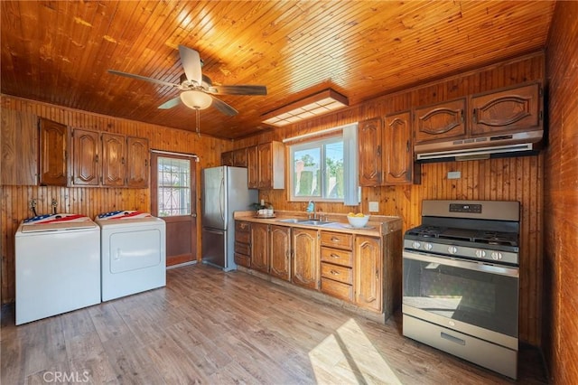 kitchen with appliances with stainless steel finishes, light wood-style floors, separate washer and dryer, plenty of natural light, and under cabinet range hood