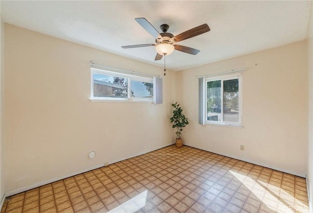 empty room featuring a ceiling fan, a wealth of natural light, and tile patterned floors