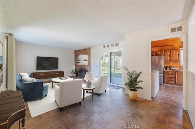 living area featuring a fireplace, visible vents, and a textured ceiling