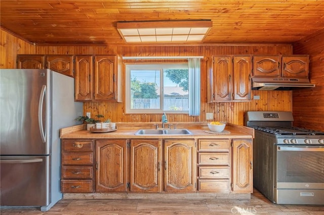 kitchen featuring stainless steel appliances, brown cabinets, wood walls, and under cabinet range hood