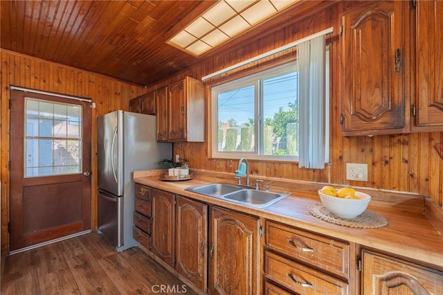 kitchen featuring dark wood-type flooring, freestanding refrigerator, a sink, wooden walls, and wooden ceiling