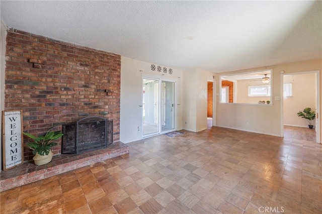 unfurnished living room with a brick fireplace, baseboards, and a textured ceiling