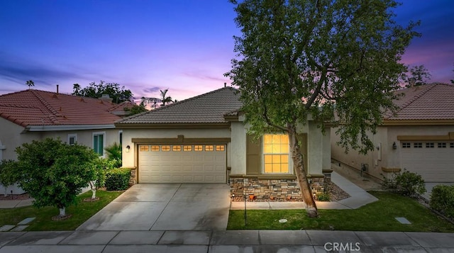 single story home with a tile roof, stucco siding, an attached garage, stone siding, and driveway