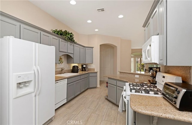 82745 Odlum Dr, Indio, CA 92201 - kitchen with white appliances, gray cabinets, arched walkways, recessed lighting, and light stone countertops