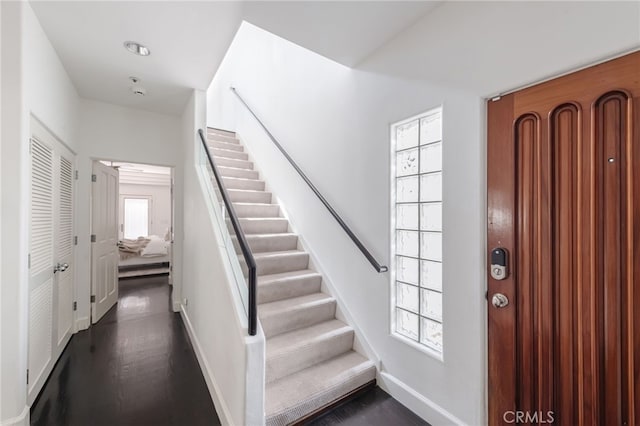 entryway with stairs, baseboards, and dark wood-style flooring