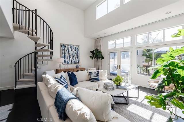 living area featuring a wealth of natural light, a high ceiling, dark wood-style flooring, and stairs