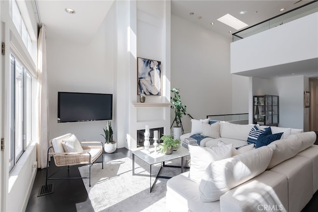 living room featuring visible vents, a healthy amount of sunlight, a towering ceiling, and wood finished floors