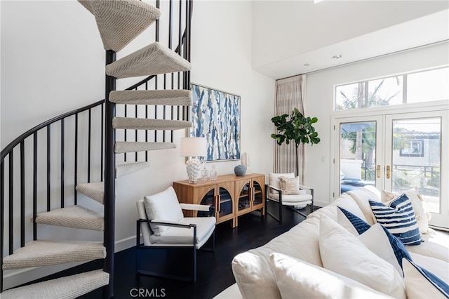 living area featuring stairway, wood finished floors, baseboards, french doors, and a towering ceiling