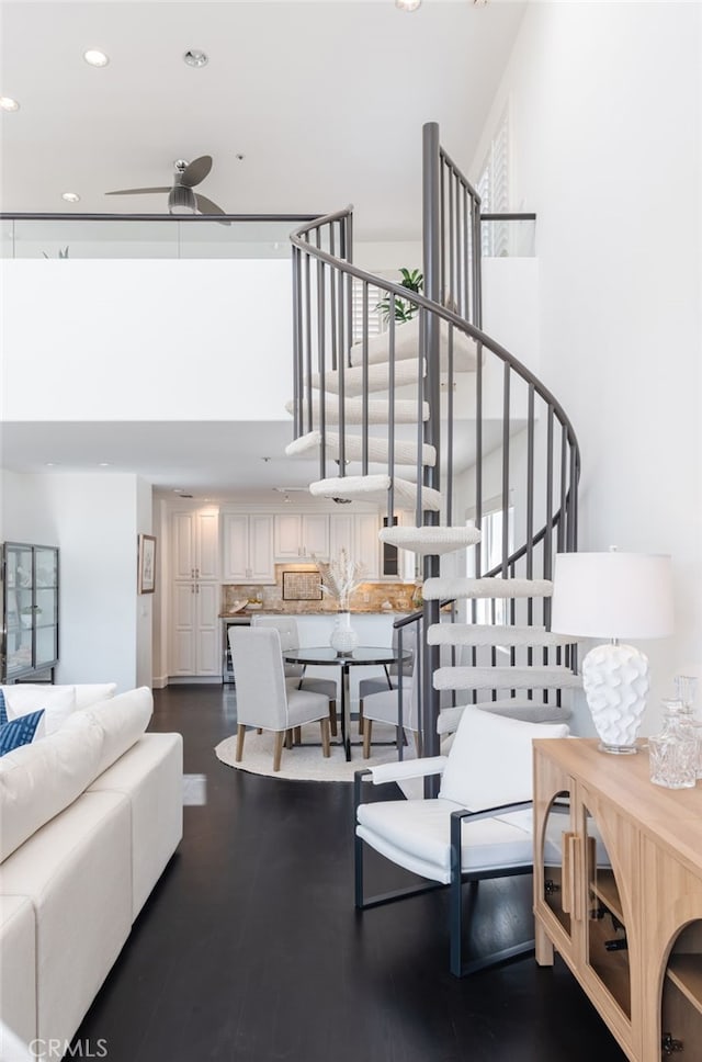 living room featuring recessed lighting, a high ceiling, dark wood-style floors, and stairs