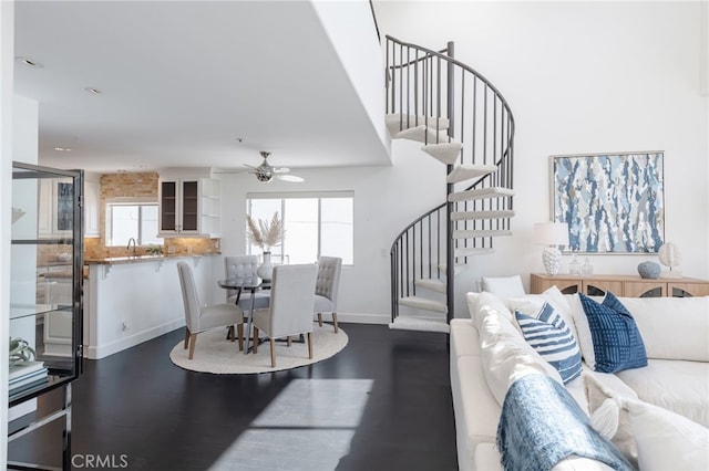 living area featuring ceiling fan, baseboards, wood finished floors, and stairs