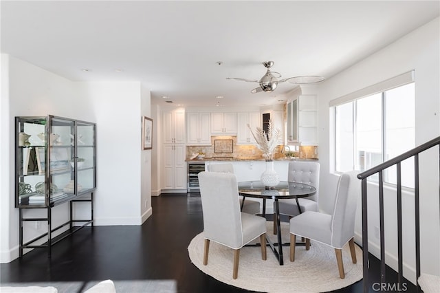 dining area featuring ceiling fan, baseboards, beverage cooler, stairs, and dark wood-style flooring