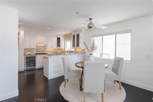 dining room featuring beverage cooler, a ceiling fan, and baseboards