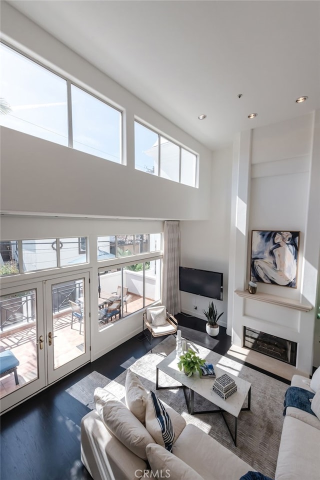 living area with recessed lighting, french doors, a high ceiling, and wood finished floors