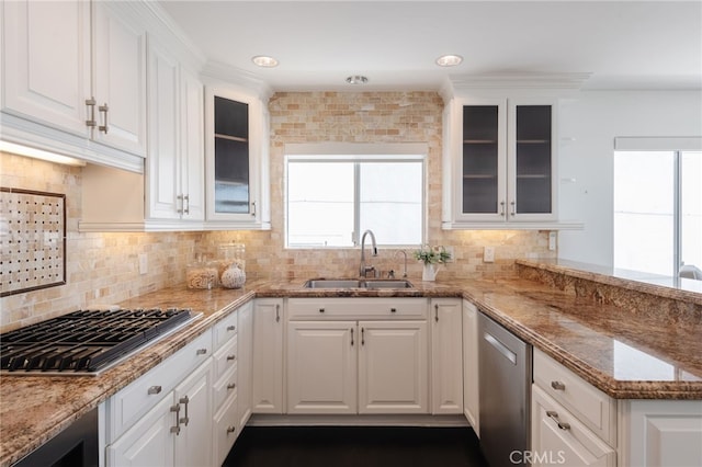 kitchen with a sink, stainless steel appliances, light stone counters, and white cabinets