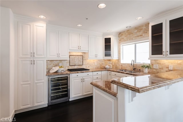 kitchen featuring beverage cooler, black cooktop, a peninsula, a sink, and a kitchen breakfast bar