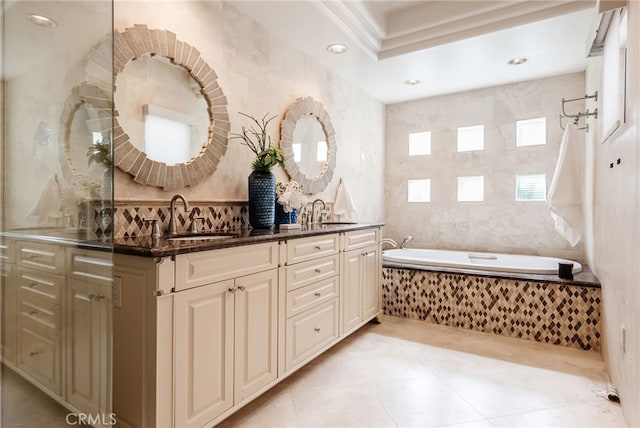 bathroom with tile patterned flooring, double vanity, a relaxing tiled tub, and a sink