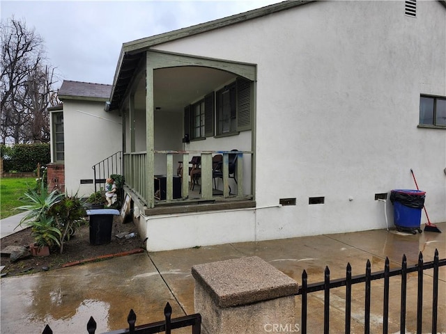 view of property exterior with a patio, crawl space, fence, and stucco siding