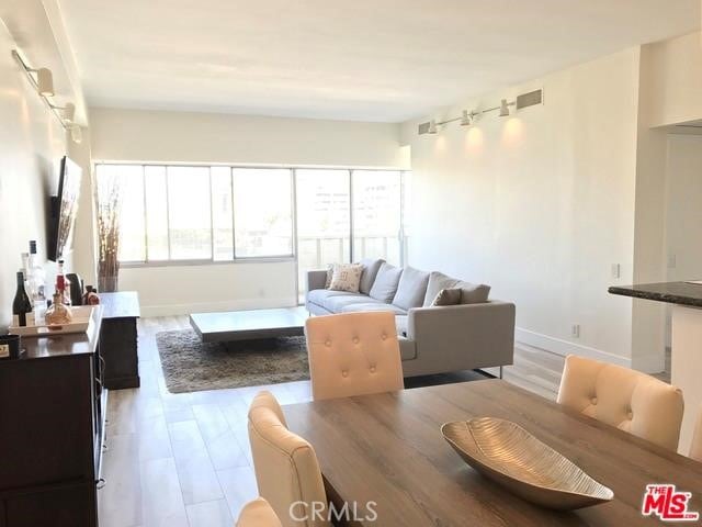 living area featuring light wood-type flooring, visible vents, and baseboards