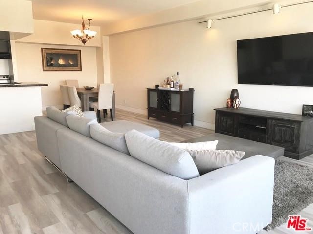 living area with a notable chandelier, light wood-style flooring, and baseboards