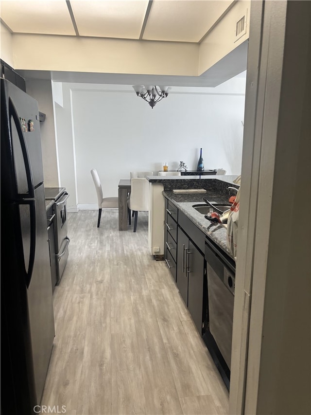 kitchen with visible vents, a sink, dark stone countertops, light wood-type flooring, and black appliances