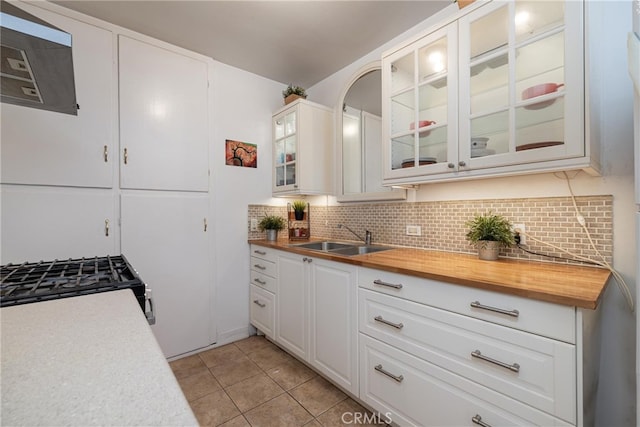 kitchen with tasteful backsplash, butcher block countertops, range with gas stovetop, and a sink