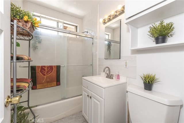 full bathroom with bath / shower combo with glass door, tasteful backsplash, vanity, and toilet